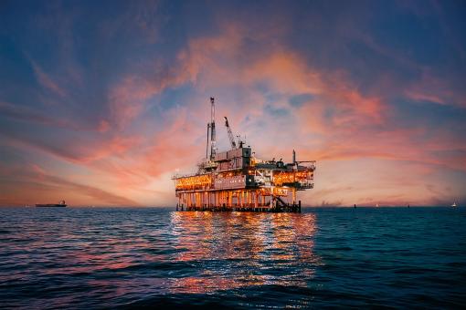 A stunning sunset photo showcases offshore oil drilling in Huntington Beach, California, with vivid hues casting a glow on industrial equipment.