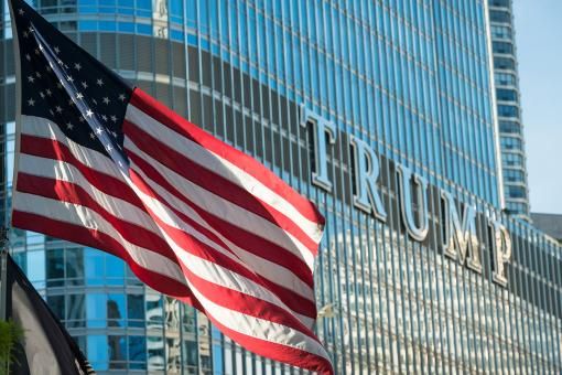 An American flag flying on the Riverwalk late in the day with the Trump Tower in the background.