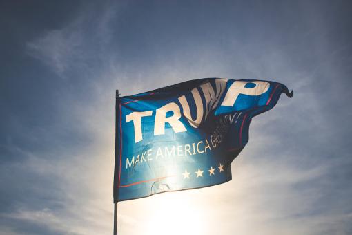 Trump flag flying with the sky and clouds in the background.